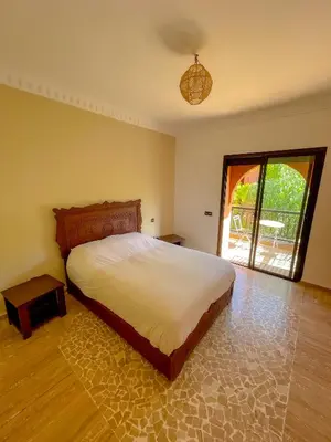 a bedroom with a large bed and a sliding glass door at Stunning Patios & Gardens Apartment in Marrakech