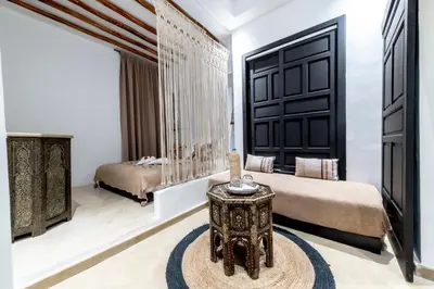 a bedroom with two beds and a table in a room at Riad Dar Yousra in Marrakech