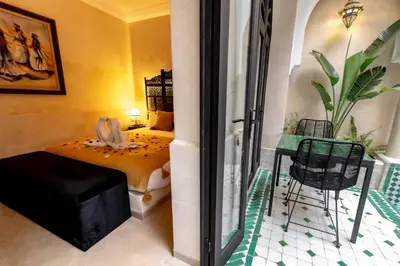 a bedroom with a bed and a table and a chair at Riad Dar Yousra in Marrakech