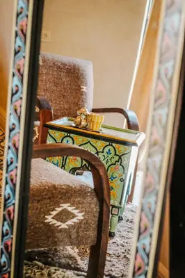 a side table sitting next to a chair in a mirror at Hotel & Spa La Ferme El Dar in Marrakech