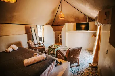 a room with a bed and chairs in a tent at Hotel & Spa La Ferme El Dar in Marrakech