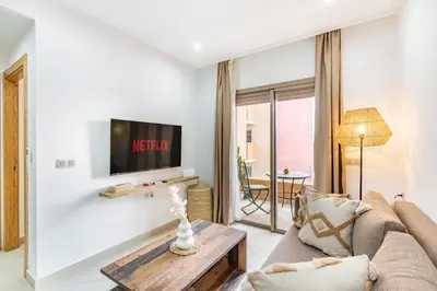 a living room with a couch and a tv at Le COSY CHIC- NEUF - Modern & Chic - Terrasse et Confort - CLIM PARKING et WIFI Gratuit ! GUELIZ in Marrakech