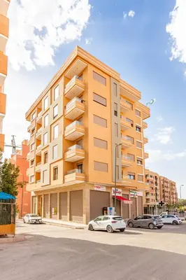 a tall building with cars parked in a parking lot at Le COSY CHIC- NEUF - Modern & Chic - Terrasse et Confort - CLIM PARKING et WIFI Gratuit ! GUELIZ in Marrakech