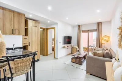 a kitchen and living room with a couch and a table at Le COSY CHIC- NEUF - Modern & Chic - Terrasse et Confort - CLIM PARKING et WIFI Gratuit ! GUELIZ in Marrakech