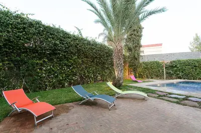 three lounge chairs sitting next to a swimming pool at Your Traditional Marrakchi Villa in Marrakech