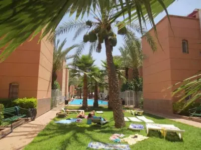 a pool with palm trees and people laying on the grass at Said MM in Marrakech
