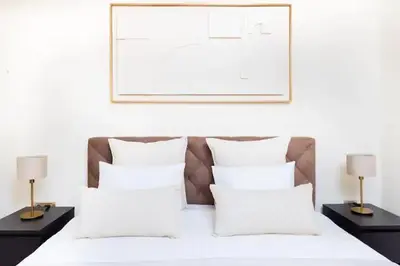 a bed with white sheets and pillows and two lamps at Appartement prestigia golf accès piscine in Marrakech