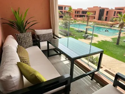 a living room with a glass table and a pool at Domaine de Noria Isli 2 - Magnifique 2 chambres - Vue directe sur la piscine in Marrakech