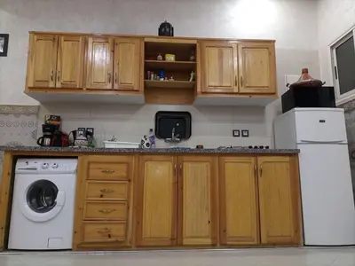 a kitchen with wooden cabinets and a white dishwasher at MARRAKECh TYPICAL & CONFORT APPARTEMENT in Marrakech
