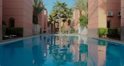 a large swimming pool in a building with palm trees at MARRAKECh TYPICAL & CONFORT APPARTEMENT in Marrakech