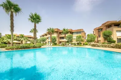 a large swimming pool in a resort with palm trees at Stylish In Prestigia Area Pool View in Marrakech