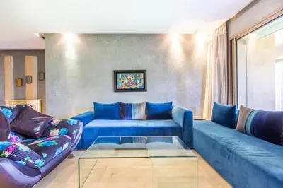 a living room with a blue couch and a glass table at Front de piscine en rez de Jardin a Prestigia in Marrakech
