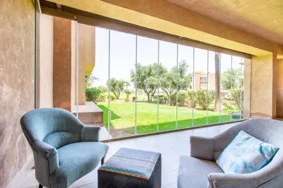 a living room with two chairs and a large window at Front de piscine en rez de Jardin a Prestigia in Marrakech