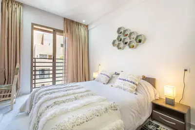 a white bedroom with a bed and a window at Cosy Appt au Coeur de Gueliz in Marrakech