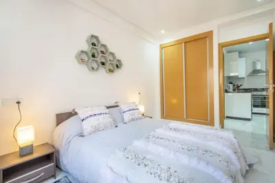 a bedroom with a large white bed and a kitchen at Cosy Appt au Coeur de Gueliz in Marrakech