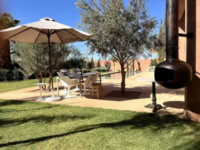 a patio with an umbrella and a table and chairs at Villa Sissi Marrakech in El Rhechat