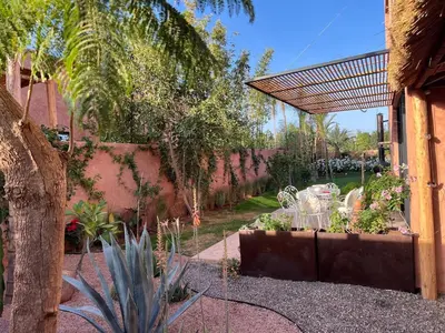 a patio with a table and chairs in a garden at Villa Sissi Marrakech in El Rhechat