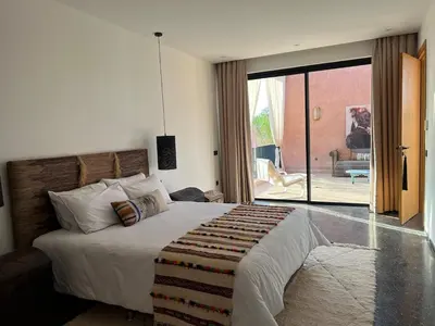 a bedroom with a large bed and a sliding glass door at Villa Sissi Marrakech in El Rhechat
