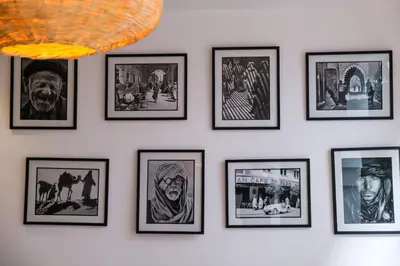 a wall of framed pictures on a white wall at Riad Dar Jamila Breakfast 10mn to Jamaa Al Fna in Marrakech