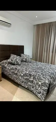a bed with a black and white comforter in a bedroom at Cozy appartment in Marrakech