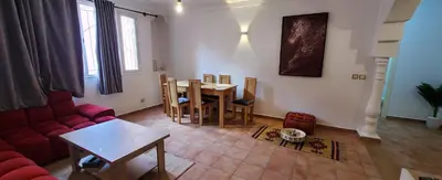 a living room with a table and a red couch at Well-equipped apartment for rent in Marrakech