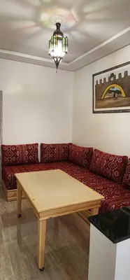a living room with a red couch and a wooden table at الراحة والسلامة مراكش in El Gouassem