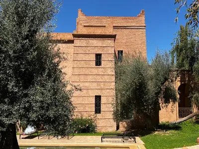 a building with trees and a bench in front of it at Villa kasbah de luxe, piscine et jacuzzi chauffés, jardin tropical in Marrakech