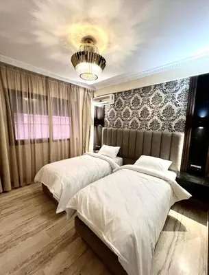 a bedroom with two beds and a chandelier at L'Escapade Douce Marrakech in Marrakech