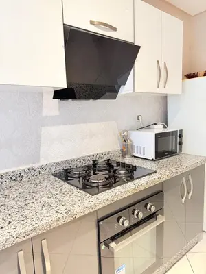 a kitchen with a stove and a microwave at Appartement N15 Lumineux Calme & Centre-ville in Marrakech
