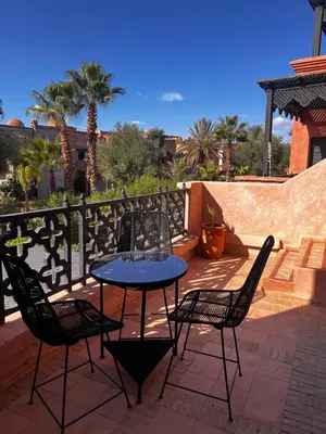 a table and chairs on a patio with palm trees at Your Getaway Oasis in the Lush Resort in Marrakech