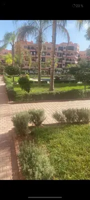 a park with palm trees and a building in the background at Premium village A644 in Marrakech