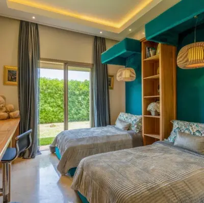 a bedroom with two beds and a desk and a window at Heated Pool Villa in Marrakech