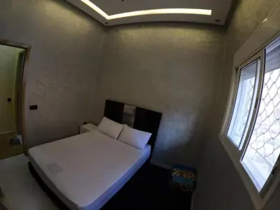 a small bedroom with a white bed and a window at Appartement en résidence in Marrakech