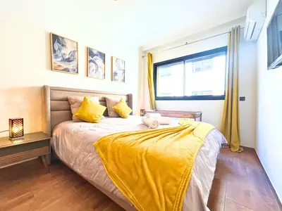 a bedroom with a bed with yellow sheets and a window at Le Coup de cœur de Guéliz avec Piscine et Parking in Marrakech