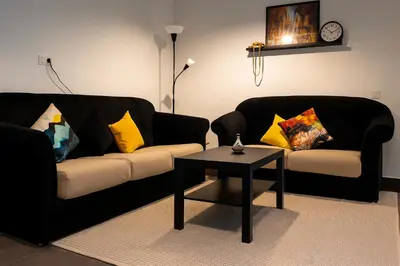 a living room with two black couches and a table at Cozy & Bright Apartment with a Panoramic View in Marrakech
