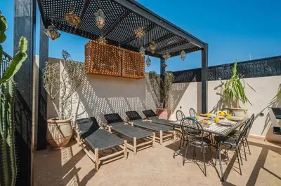a patio with a table and chairs and a pergola at Riad Dar Davia - Jacuzzi Rooftop - Breakfast in Marrakech