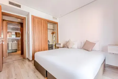 a white bedroom with a large white bed and wooden floors at Bright and Stylish Apartment Center of Marrakech in Marrakech
