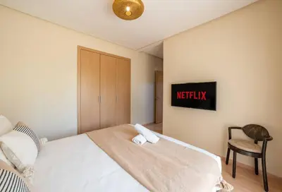 a bedroom with a white bed and a chair at Trois chambres et Jardin Prive a Prestigia in Marrakech