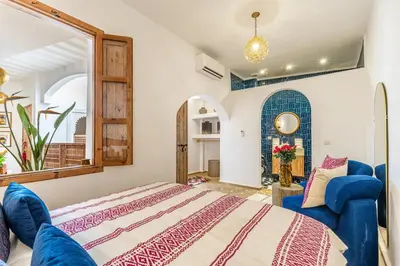 a bedroom with a bed and a blue chair at Riad Dar Catalia-Exclusive&HeatedPool-FreeBreakfas in Marrakech