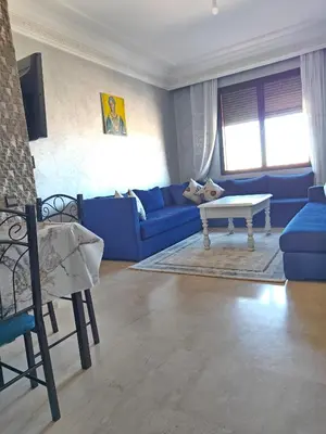 a living room with a blue couch and a table at Séjour Familial à Marrakech in Marrakech