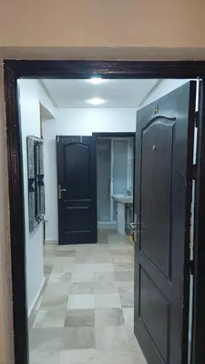a hallway with two black doors and a tile floor at Le stratégique a 10mn de l'aéroport face gare Ctm Hivernage in Marrakech