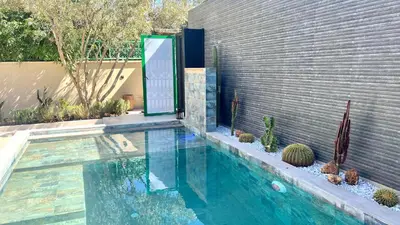 a swimming pool in a yard with cactuses and a wall at Villa de rêve avec Piscine privée & Petit-déj gratuit in Ouled Rahou