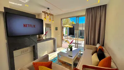 a living room with a couch and a tv at Villa de rêve avec Piscine privée & Petit-déj gratuit in Ouled Rahou