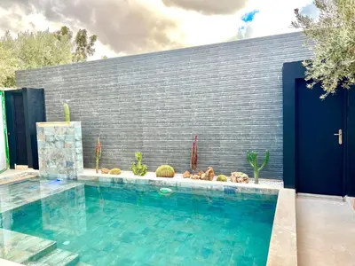 a swimming pool in front of a wall with cactus at Villa de rêve avec Piscine privée & Petit-déj gratuit in Ouled Rahou