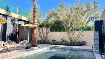 a swimming pool with chairs and a table and trees at Villa de rêve avec Piscine privée & Petit-déj gratuit in Ouled Rahou