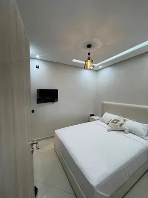 a bedroom with a white bed and a television at IMMOB Basma in Marrakech