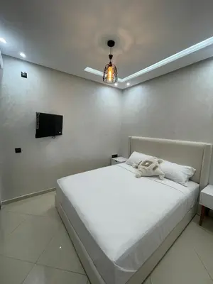 a bedroom with a white bed and a tv at IMMOB Basma in Marrakech