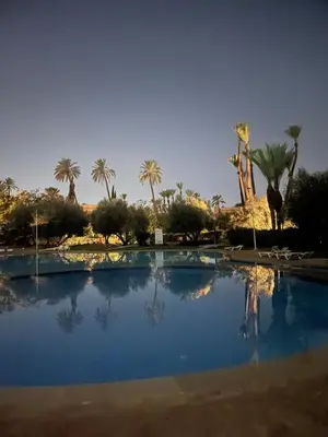 a swimming pool in the middle of a desert with palm trees at Dar lala habiba in Marrakech