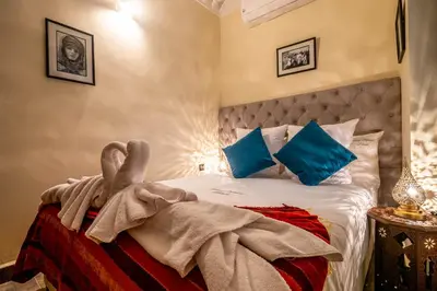 a bedroom with a large bed with blue pillows at Riad Kamal Deluxe in Marrakech