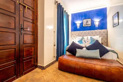 a bedroom with a large wooden bed with blue walls at Riad Kamal Deluxe in Marrakech